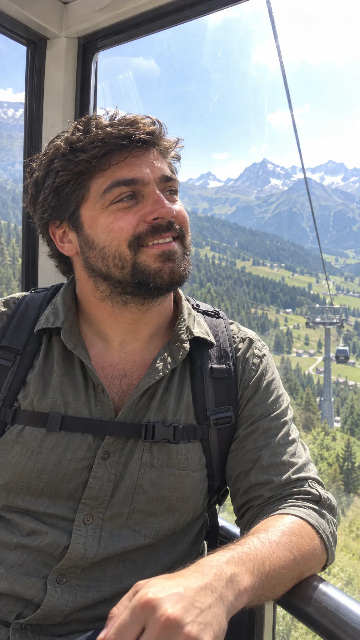 Riding a cable car in a backpack, snow-capped mountains through the window