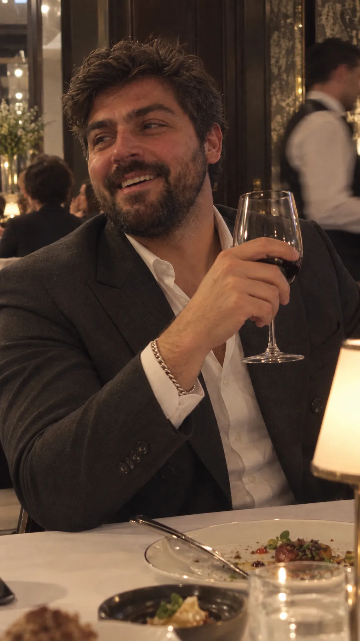 Laughing over red wine at a candlelit dinner in a grand dining room